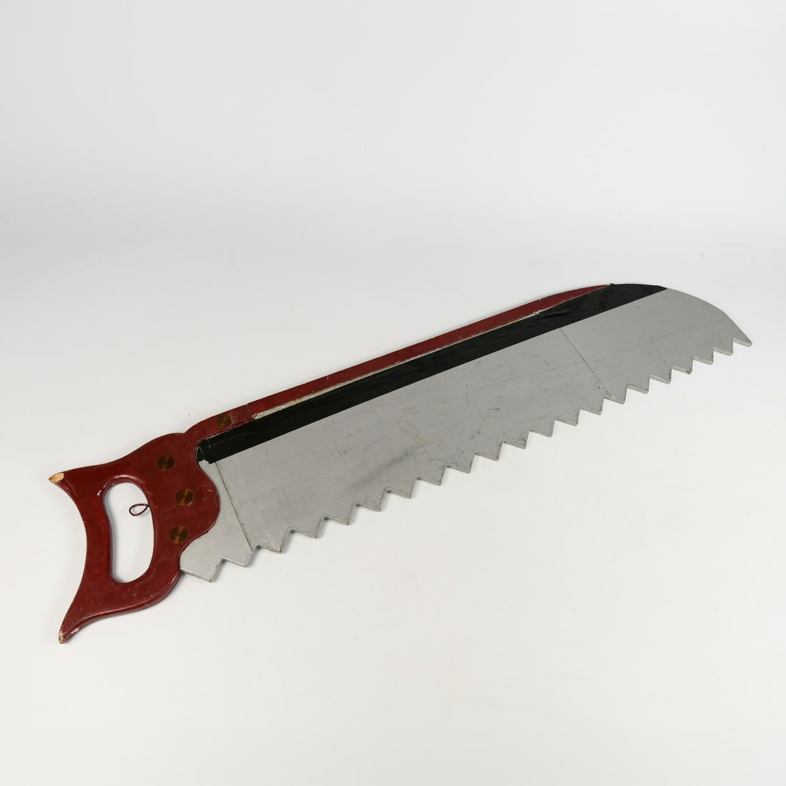 Oversized Decorative Wood Saw: Large decorative hand saw with wooden handle and oversized serrated blade. Suitable as a prop or decorative piece for workshop, theatre, or themed interiors. Condition: Used with signs of wear consist