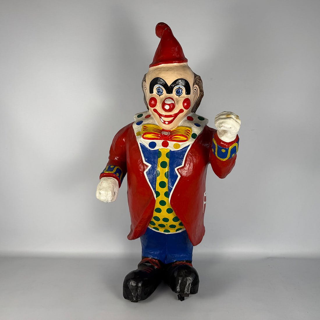 Vintage Papier-Mâché Clown Figurine in Red Coat: Decorative vintage papier-mâché clown figure wearing a red coat, pointed hat, and colorful costume with polka-dot details. A cheerful circus-style character, suitable as a display or themed decorati