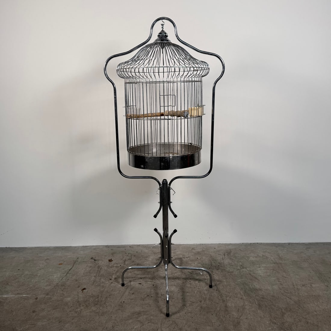 Birdcage ON STAND: Decorative metal birdcage mounted on a freestanding metal stand with three legs. Featuring a domed top, wire construction, and internal perch. Condition: Used with signs of age and wear. Suitable as