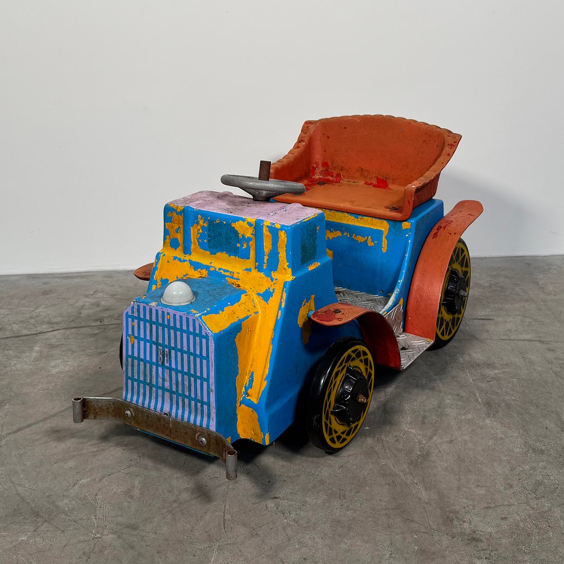 Vintage Hand-Painted Plastic Toy Car - Blue, Yellow, Red: Vintage children’s ride-on toy car made of molded plastic, finished in bright blue with yellow and red hand-painted details. The vehicle features a classic early automobile-inspired design with a fr