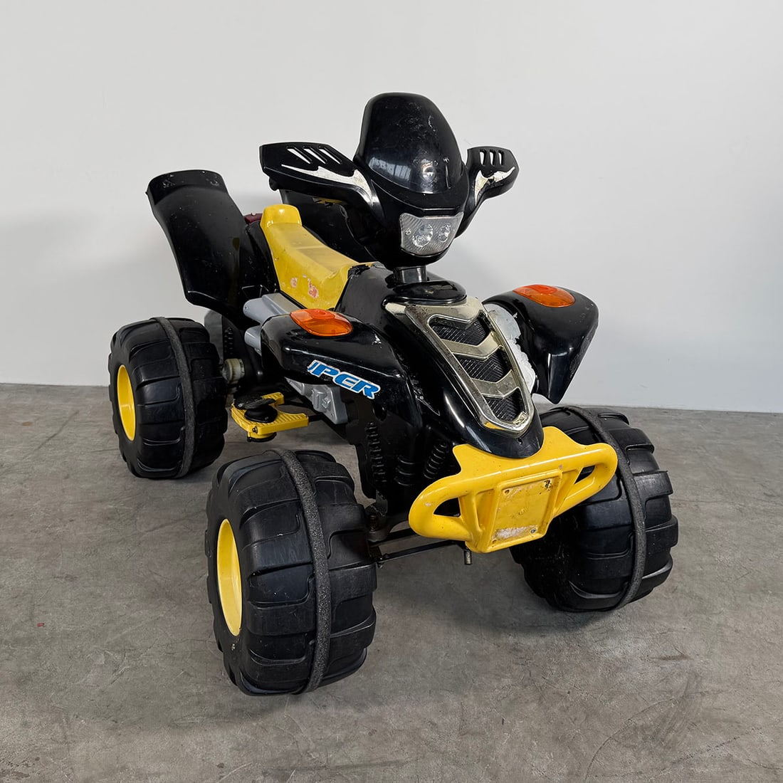 Electric Kids Quad Bike - Fully Working Condition Black and yellow: Electric children’s quad bike in a sporty black and yellow color scheme. The quad features large plastic wheels with rugged tread, a molded seat, handlebars, and decorative engine details that give