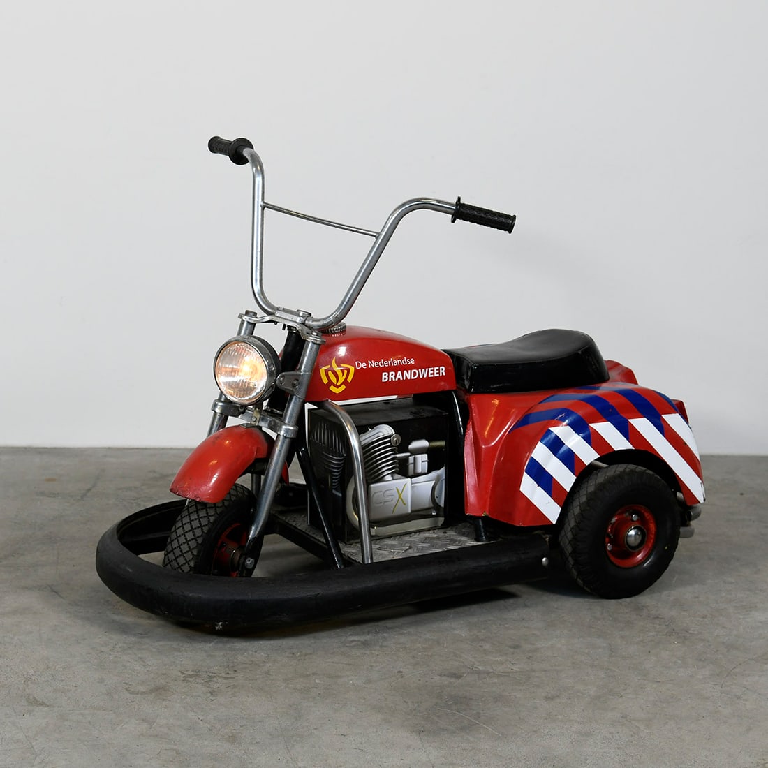 "De Nederlandse Brandweer" 12-Volt Electric Children's Bike: The Electric Children's "De Nederlandse Brandweer" vehicle is a modeled after the Dutch fire brigade. Operates on a 12-volt battery system and includes functional lights. The bike is in a good working