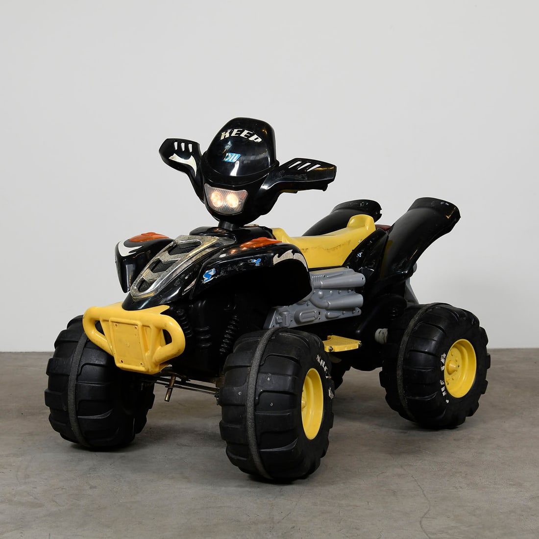 Electric Yellow and Black Children's Quad Bike with a New Battery: This electric children's quad bike features yellow and black plastic body designed with a sporty, aggressive profile for young riders. The quad has been updated with a new battery and is in a good wor
