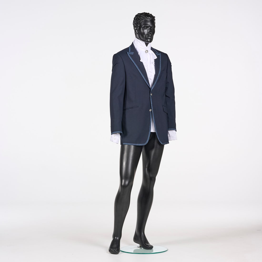 Suit Jacket with Ruffled Shirt and Brooch from the Royce Collection: Suit jacket with ruffled shirt and a brooch from the Royce Collection. This navy blue suit jacket features a single-breasted design with a two-button closure and a distinctive light blue braided trim.