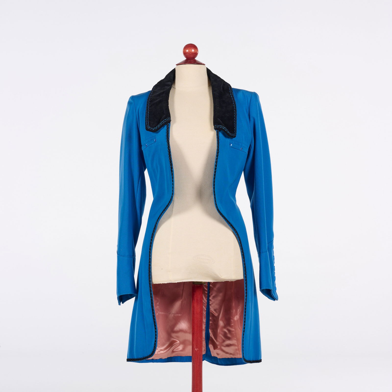 Original Bright Blue Victorian-inspired Tailored Coat from the Royce Collection: This bright blue tailored coat from the Royce Collection features a Victorian-inspired silhouette with long sleeves and a contrasting black velvet collar. The garment is detailed with intricate black