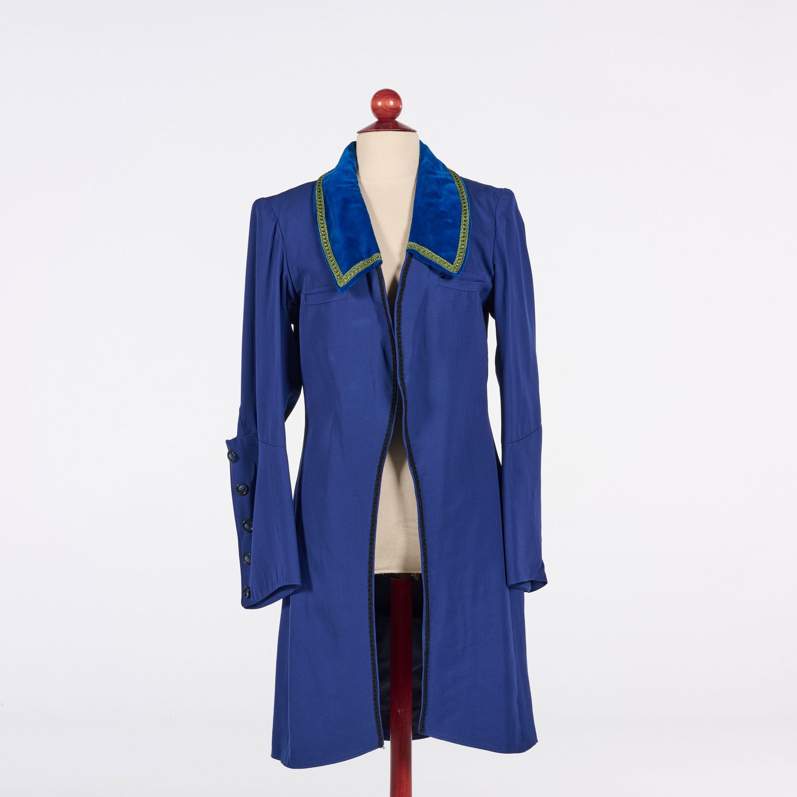 Original Royal Blue Frock Coat from the Royce Collection: This royal blue frock coat from the Royce Collection features a structured, knee-length silhouette with an open front and a tailored, seamed back. The garment is defined by a large, pointed collar cra