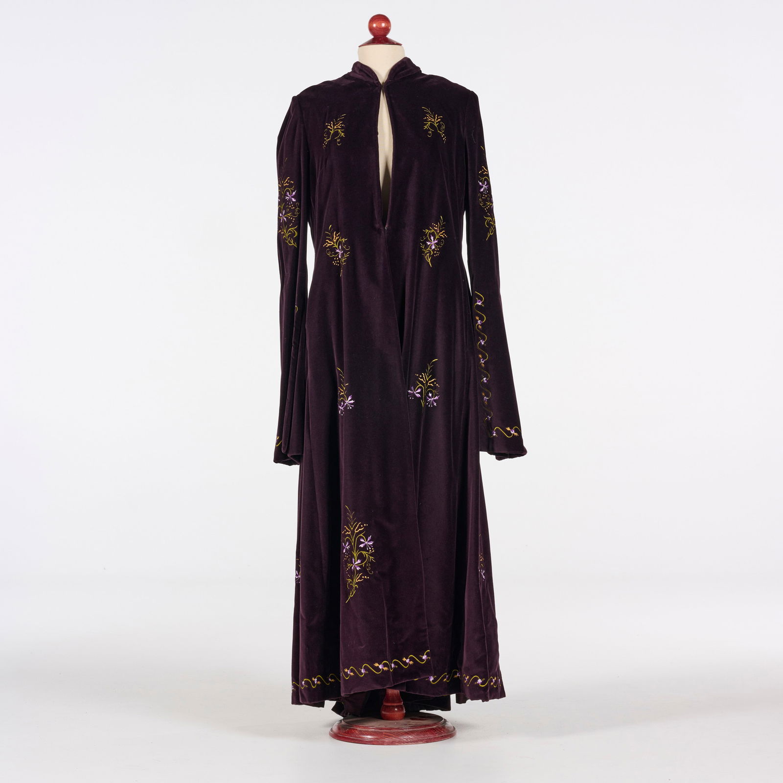 Original Velvet Floor-length Coat with Floral Embroidery from the Royce Collection: This original floor-length coat from the Royce Collection is crafted from deep plum velvet and features an open-front design with a high, standing collar and long, flared sleeves. Delicate floral embr