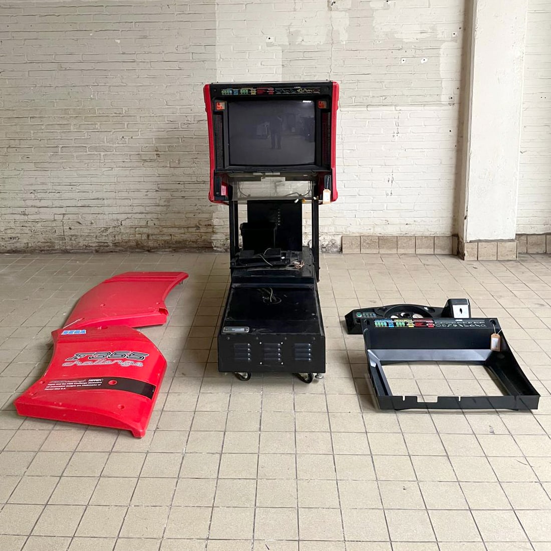 F355 Challenge Ferrari Arcade Game Cabinet and Parts Sega (1999): This is a lot of parts for Sega F355 Challenge Ferrari arcade racing game, originally released in 1999. Its main cabinet, internal components, and various external panels are present. The red and