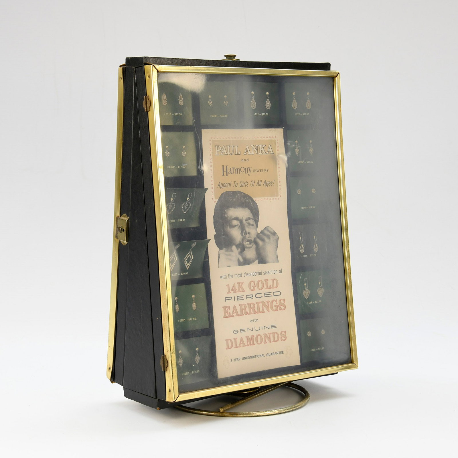 Vintage Paul Anka & Harmony Jewelry Display Case: Vintage Paul Anka & Harmony Jewelry Display Case by Sibfeld Jewelry Case Co.This display case features a black exterior with brass-toned metal trim and a clear glass front cover, mounted on a rotating