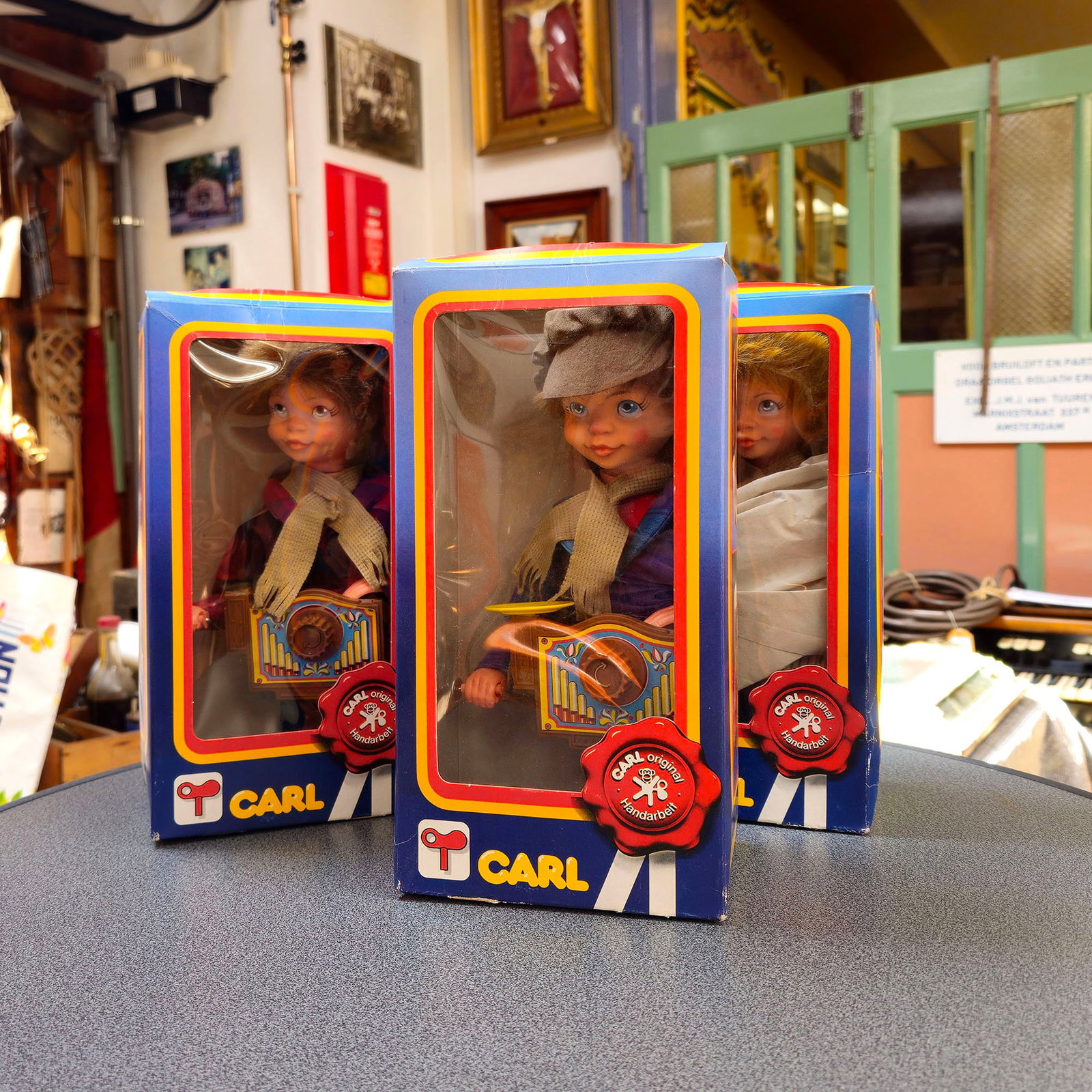 Lot of 3 CARL Wind-up Street Organ Player Automatons (ca. 1970s-1980s) from the G. Perlee Collection: This lot includes three CARL "Art-Nr. 704" wind-up automatons, each depicting a street organ player figure dressed in a cap, scarf, and colorful period clothing, holding a miniature street organ. One 