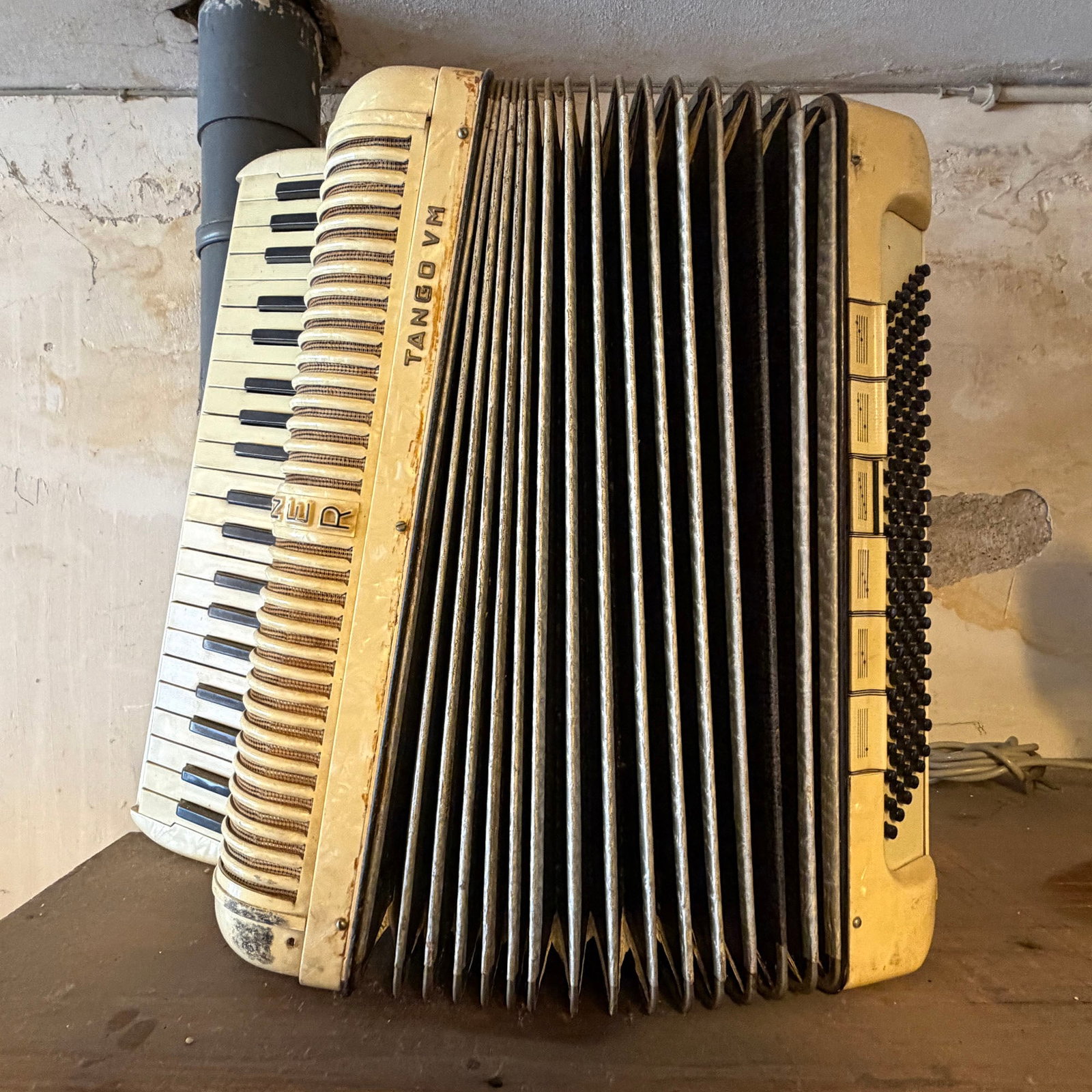 Hohner Tango VM Accordion (c. 1950s-1960s): A vintage Hohner Tango VM accordion, produced approximately between the 1950s and 1960s, featuring a cream-colored body with visible wear and discoloration consistent with age and use. Specifically ad