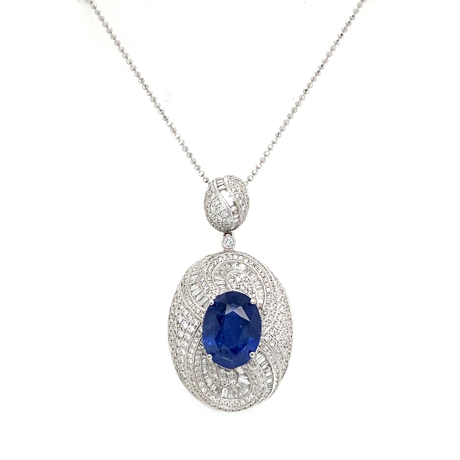 10.51 Carat Fine Blue Burma Sapphire and Diamond: Over 10 carats, this stunning oval sapphire necklace pendant will make you swoon. The large deep blue gem is surrounded by a unique design where round cut diamonds meet rows of baguette-cut diamonds.