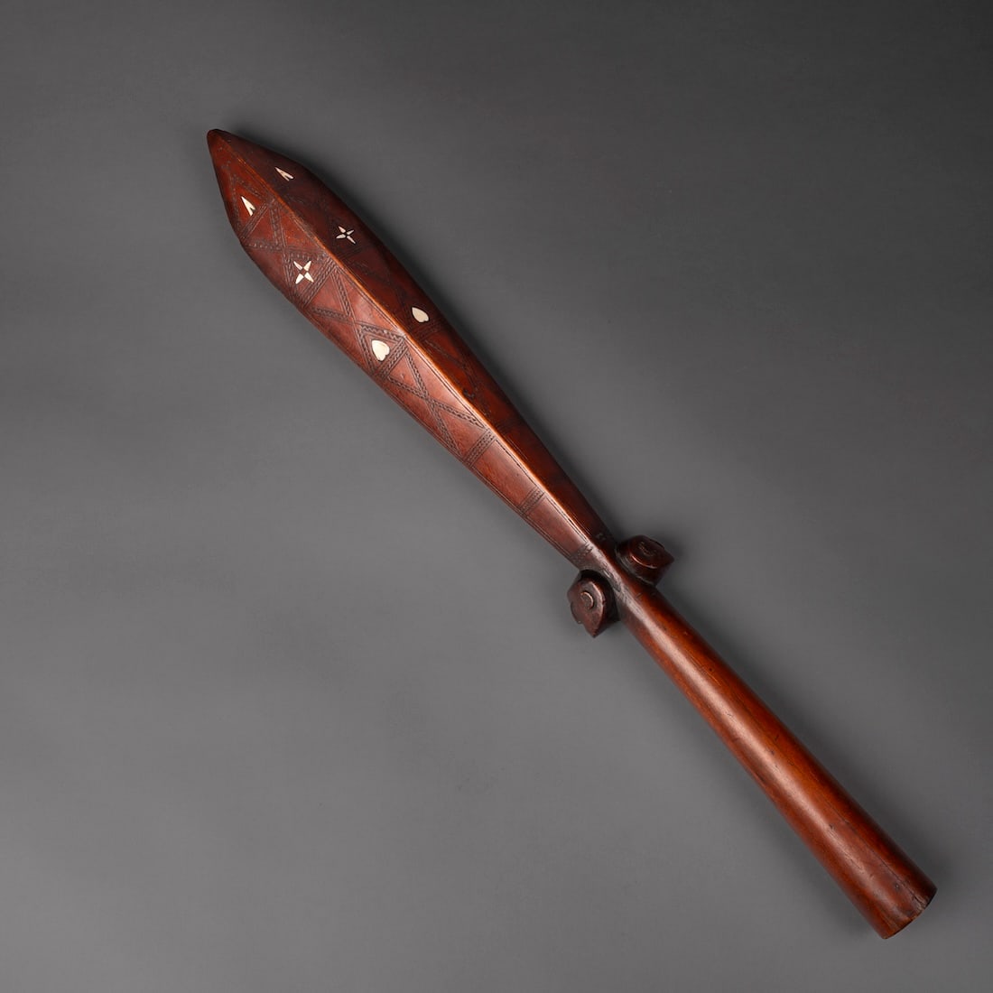 A Solomon Islands ceremonial club: The hardwood club with wide, round handle, with two heads protruding above, with a four-sided blade with geometric carved decoration and shell inlay on each side, dark brown patina. Lg. 27 3/4 in.