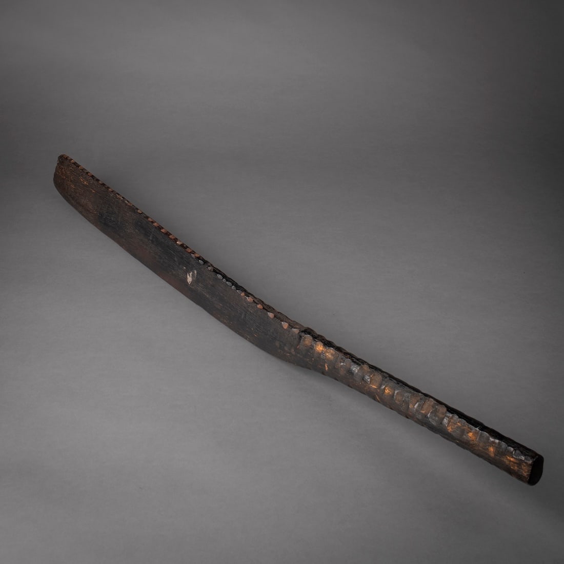 A Cook Islands war club: 19th century, the dark, hardwood club, the rounded handle with grooved surface, the long blade with flat sides, the bottom edge also grooved, the top flat, with smooth dark patina. Lg. 34 in.Provenanc