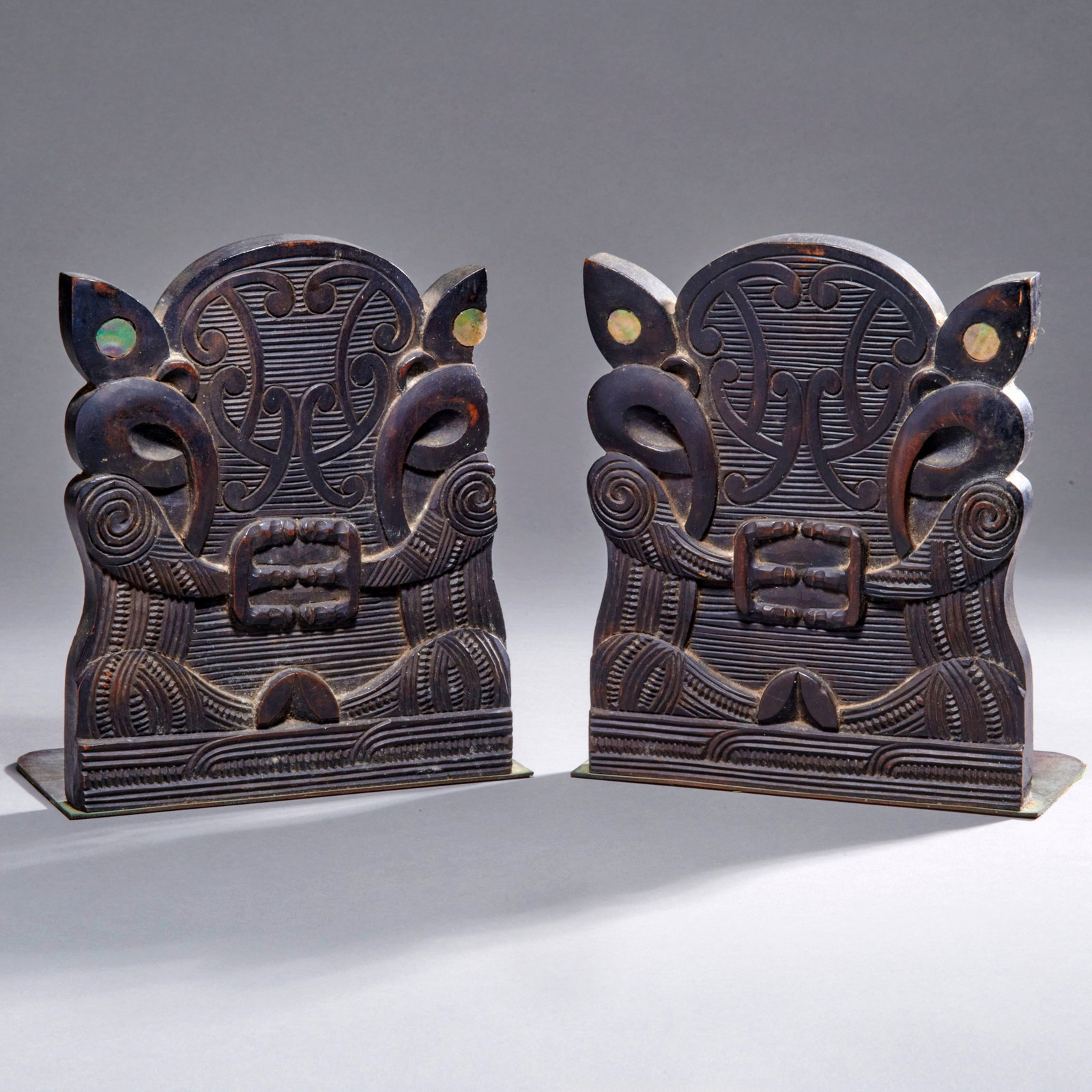 A pair of Maori carved book ends: Early 20th century, wood with metal bases, minor wood loss. Ht. 7, wd. 5 1/2 in. Provenance: Private collection, Boston, Massachusetts; Sir Peter Buck collection, prior to 1952. Shipping within the co