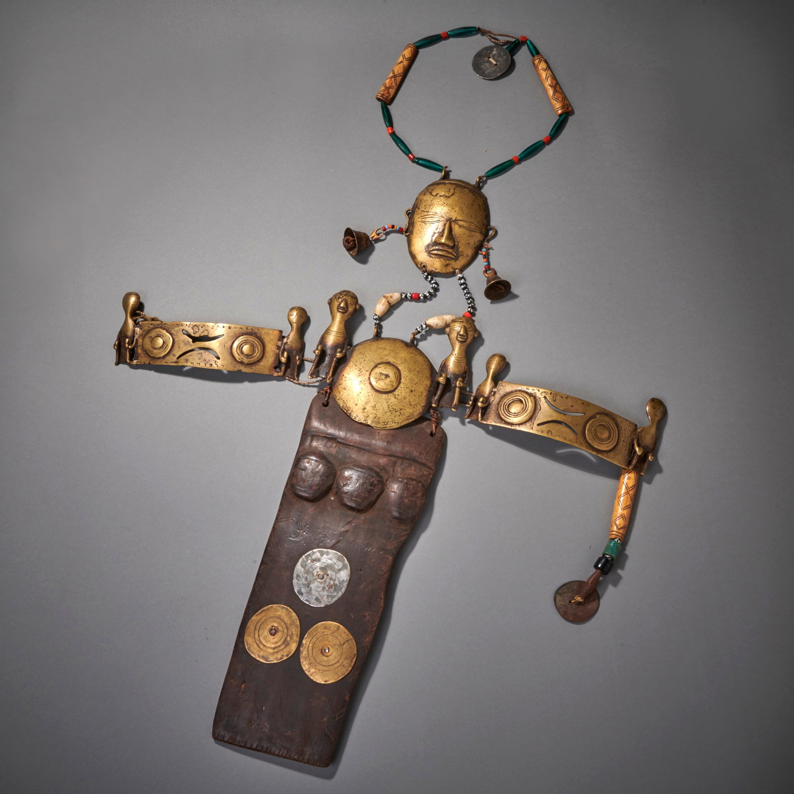A Naga Headhunter pectoral: Nagaland, early 20th Century, wood, beads and brass, the large pectoral ornament, the long, multi-bead necklace, with large brass head attached, with a bell from each ear, below two brass friezes of f
