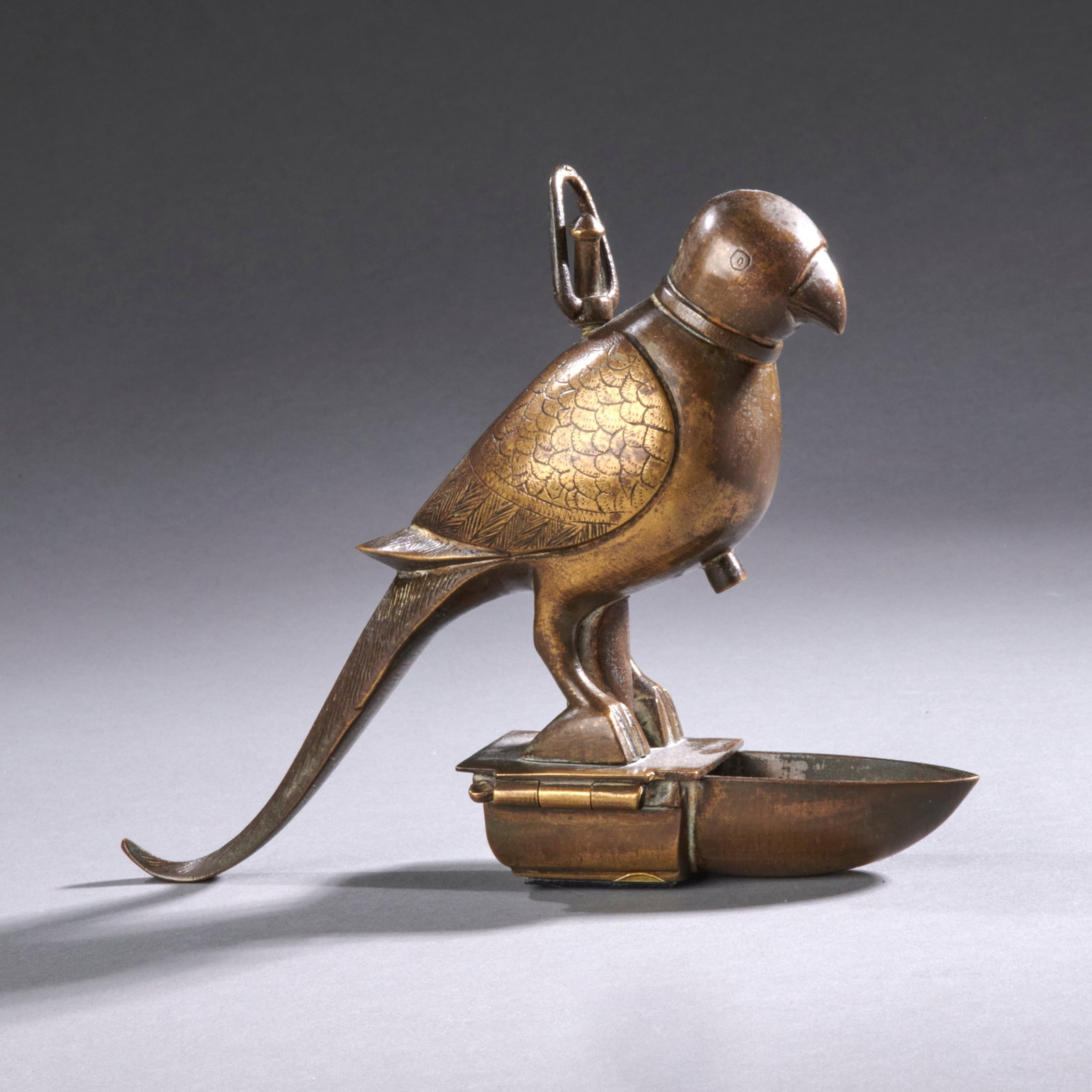 A bronze Indian bird lamp: Circa 18th century, formed of a finely cast parrot on a hinged base. Good condition with expected wear and rich golden patina. Lg. 6 1/2 in.Provenance: E & J Frankel Gallery, 1040 Madison Ave., NYC. S