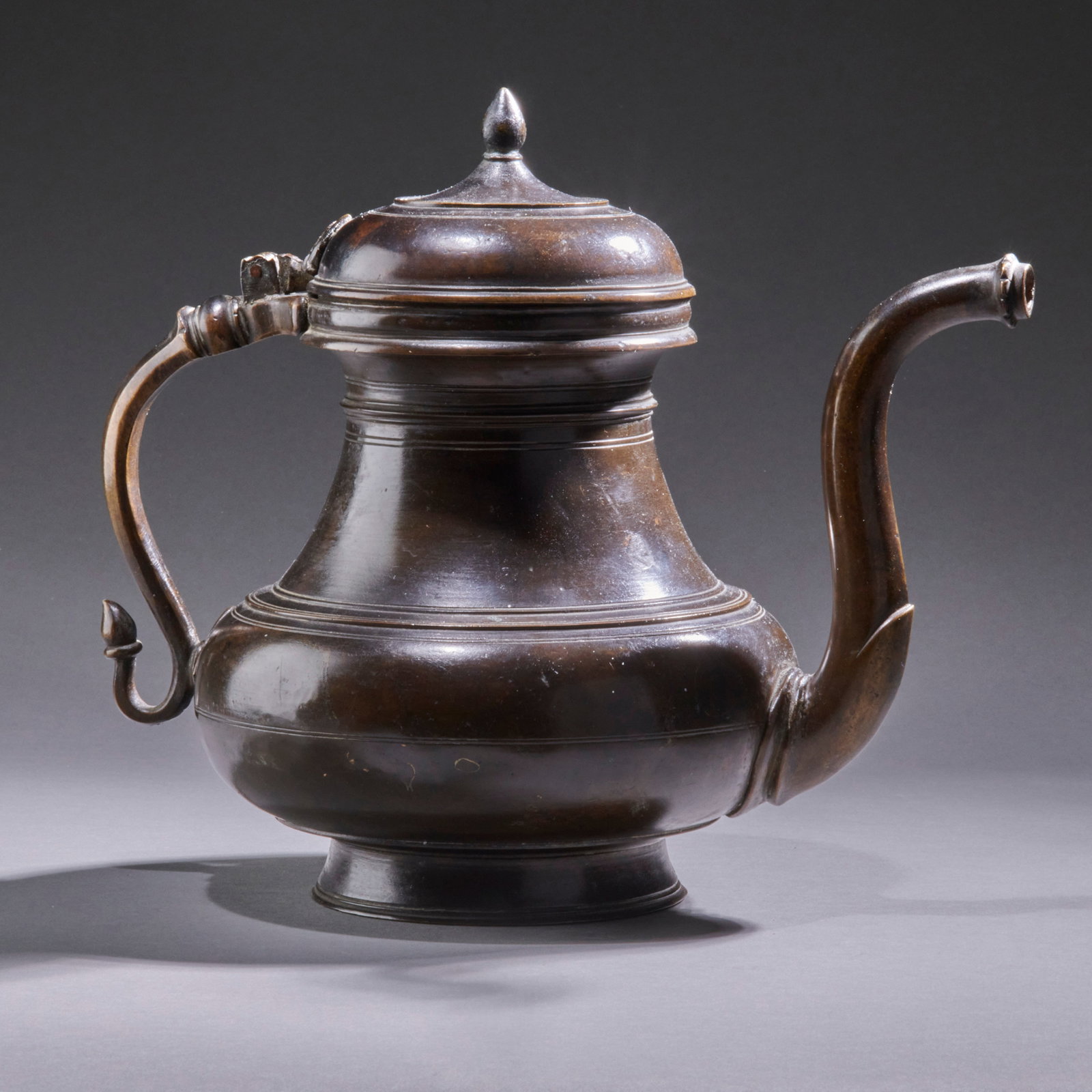 A Bronze Mughal Ewer: India, 18th century, the lidded vessel with graceful spout and handle, having a remarkable glossy brown patina. Ht. 9 in, wd. 11 1/2 in. Provenance: London market. Shipping within the continental U.S.