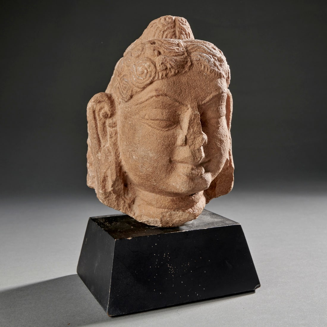 A Gupta Stone Head Of Buddha: India, circa 5th century A.D., a Gupta stone head of Buddha, mounted on a custom base. Good condition as shown. Ht. with stand: 7.3 in. (18.4 cm)Provenance: Ex Nik Douglas collection, NY; Sold at Doyl