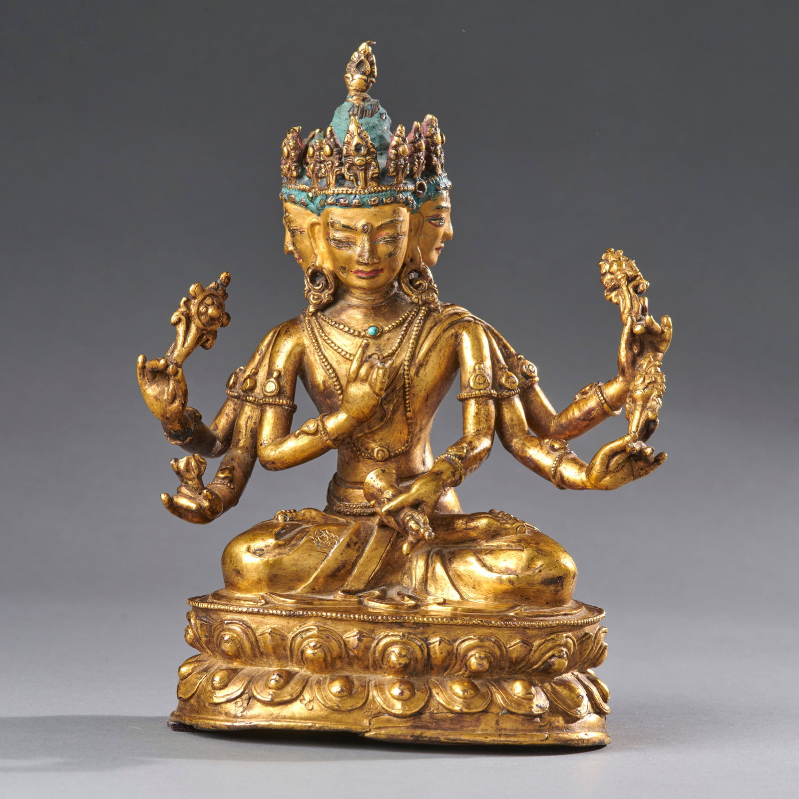 A Tibetan Bronze Usnisavijaya: Late 16th/17th century, the six-armed three-headed deity holding various attributes and ritual items, seated on a double lotus base, the faces cold gold painted, the elaborate crown encircling the blu