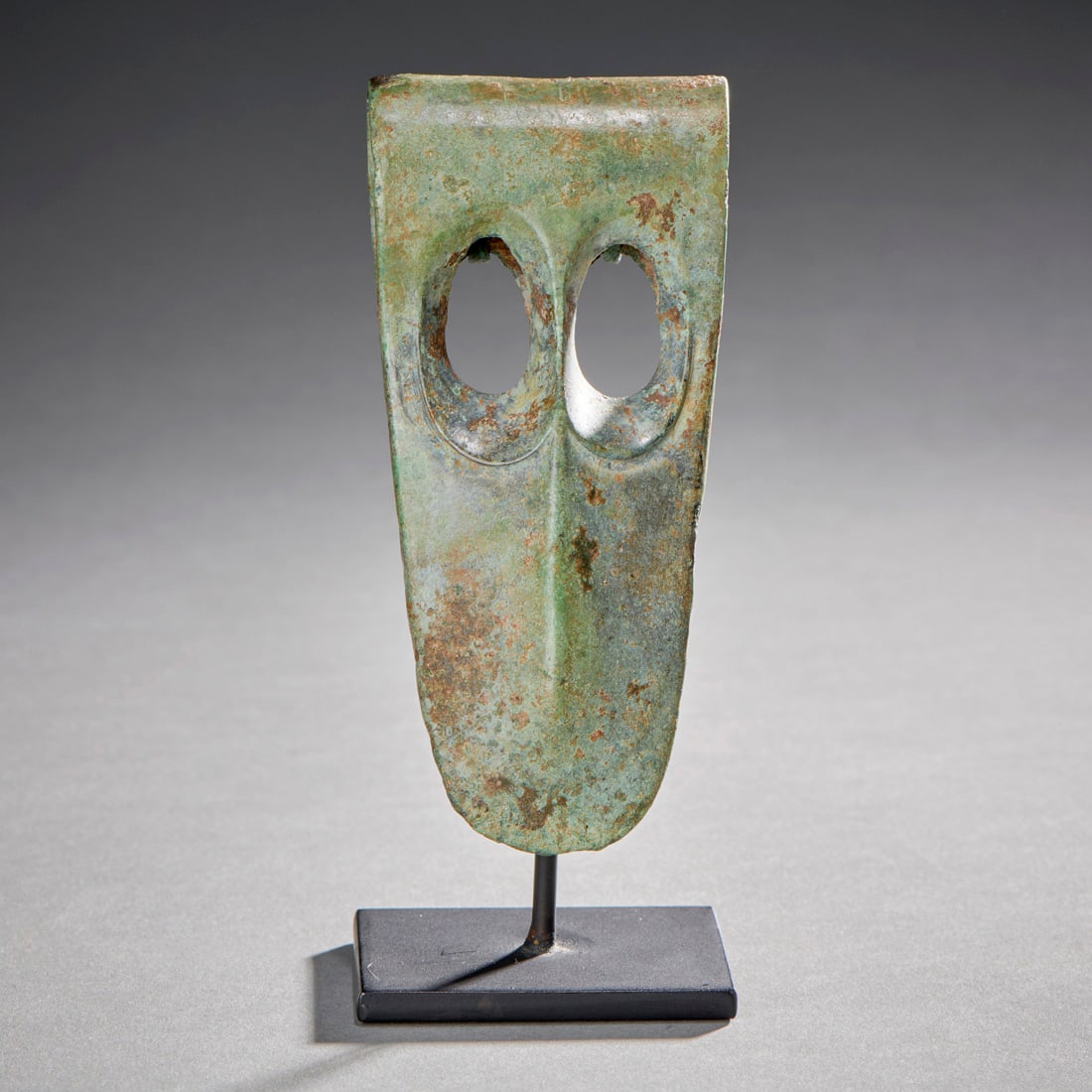 A Fine Near Eastern Bronze Axe-Head: Syria or Mesopotamia, circa 1800 B.C., of slender fenestrated type with beveled windows and “duckbill” blade, with custom stand. Ht. 4 1/8, 4 ¾ in. on stand. Provenance: Purchased at So
