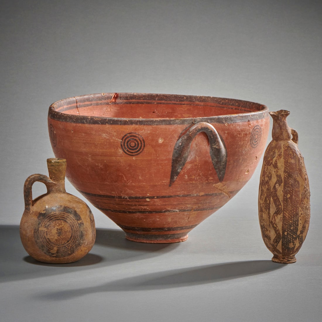 A large Cypriot Skyphos, With Two Other Cypriot Vessels: Cyprus, circa 1800 B.C.-800 B.C., a large burnished bi-chrome skyphos, a bi-chrome juggler and a rare Bronze Age lentoid flask with linear and zigzag decorations. The skyphos repaired from original fr