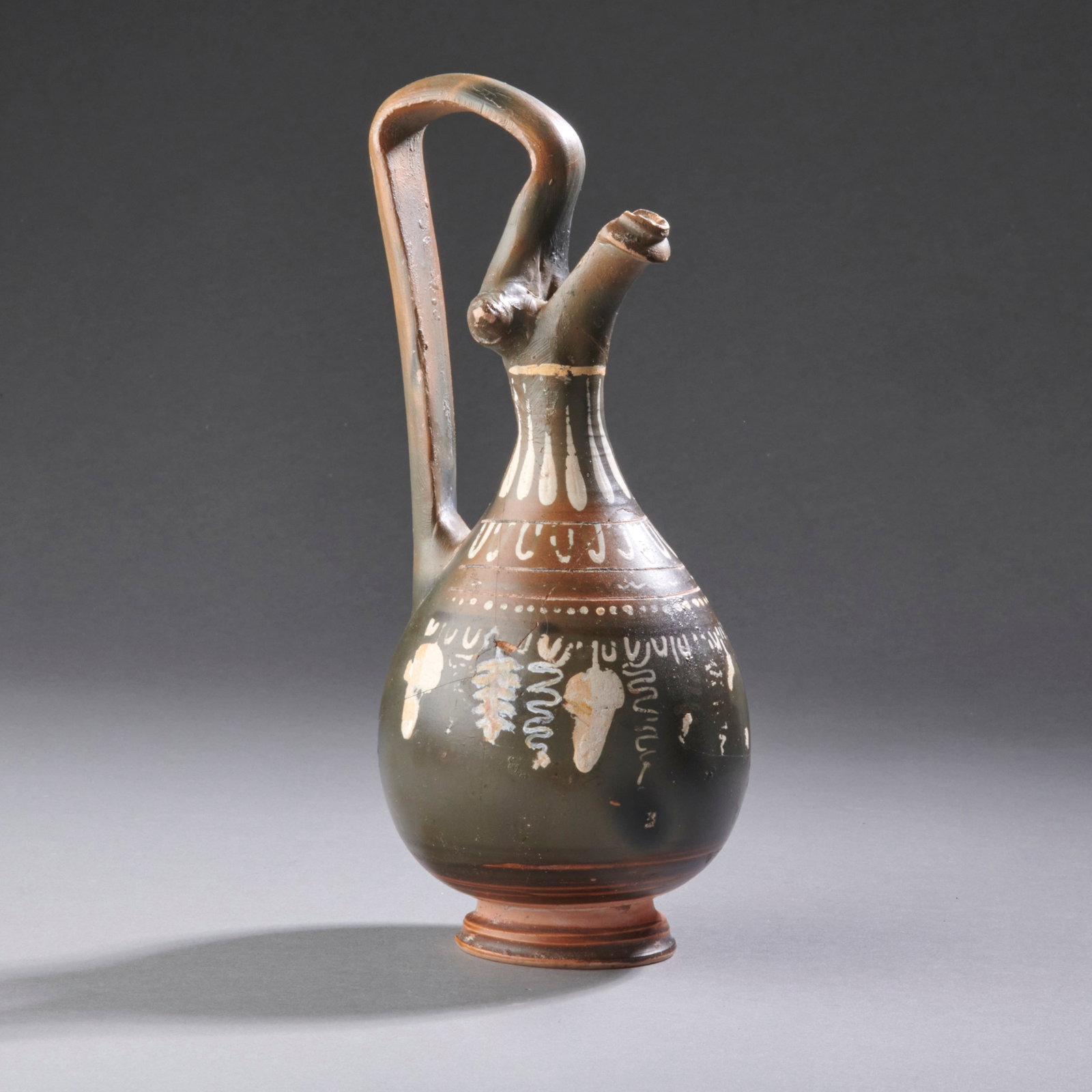 An Ancient Greek Lekythos: Southern Italy, circa 4th century B.C., of characteristic form and in Gnathian style, with remains of white and yellow painted decoration over a black glaze, an old tag at the bottom, “Harlan Berk a