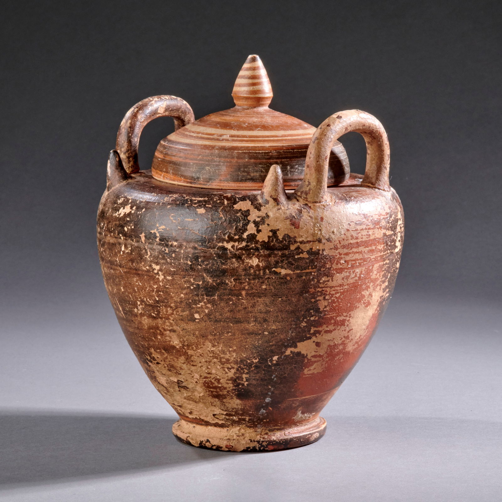 A Greek Pottery Vessel: Magna Graecia, circa 4th century B.C., a South Italian marriage vessel (lebes gamikos), retaining its original lid. Surface wear, losses to lid rim, foot and one pointed shoulder projection. Ht. 6 1/2