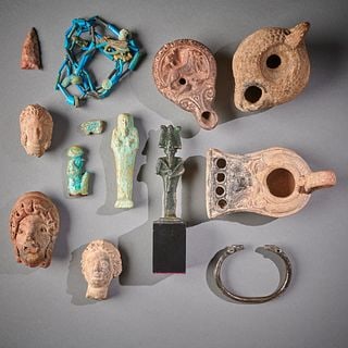 An Antiquity Group: Circa 5th century B.C. - 2nd century A.D., featuring three Greek terracotta heads, three oil lamps, a faience shabti, Horus appliqué, wedjet eye, and necklace, also a mounted bronze Osiris, a neolith