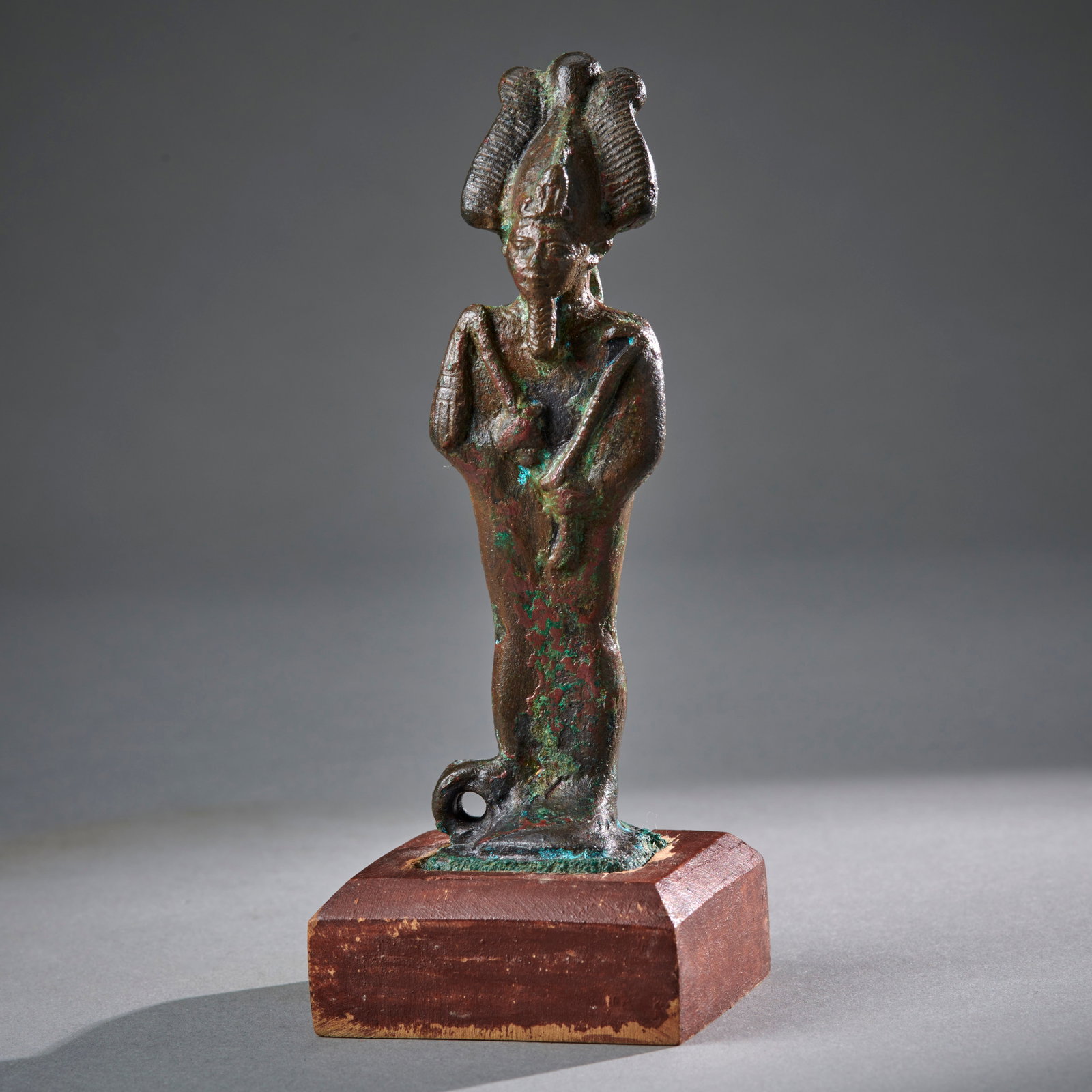 An Egyptian Bronze Osiris: 26th Dynasty, circa 6/4th century B.C., the bronze figure of Osiris, an unusually finely modeled example for this size, in very good condition, mounted on a custom wood base. Ht. 4 1/8 in. ht. with ba