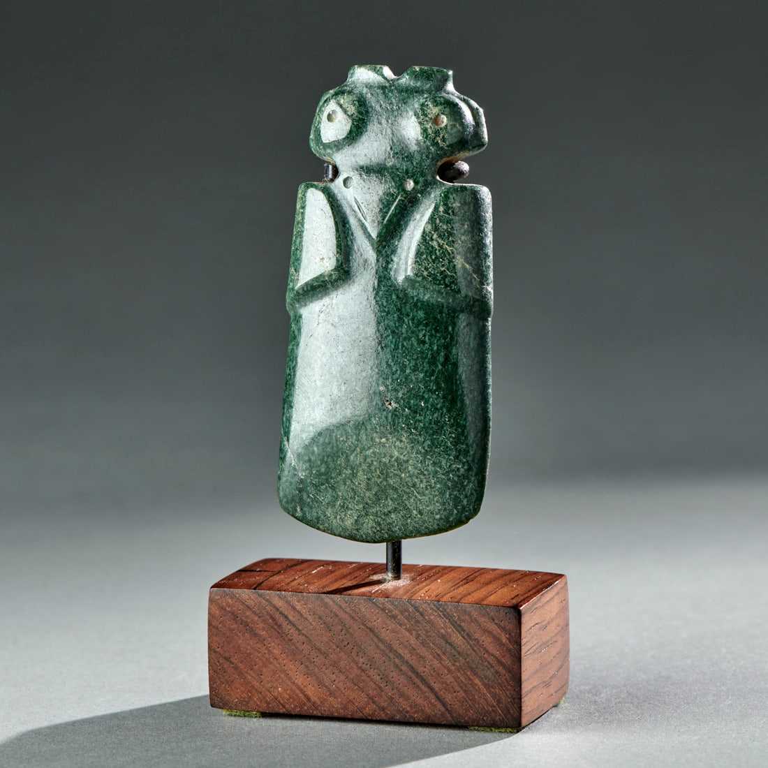 A Jade Parrot Pendant: Costa Rica, circa 8-12th century, the avian-form pendant pierced at the neck for suspension, glossy deep green stone, custom stand. Good condition. Ht. 2 3/4, 3 ¾ in. with stand. Provenance: Pu