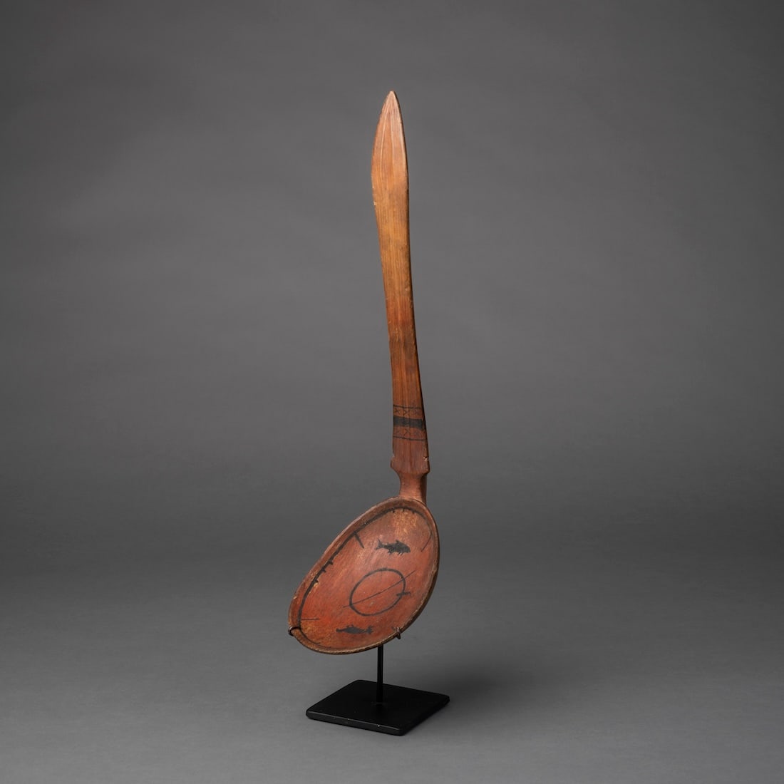 An Eskimo Polychrome Spoon: Alaska, late 19th century, the oval scoop decorated with seal and fish imagery, together with a circular fishing hole in the middle, the long handle with a flat front and band decoration, mounted on a