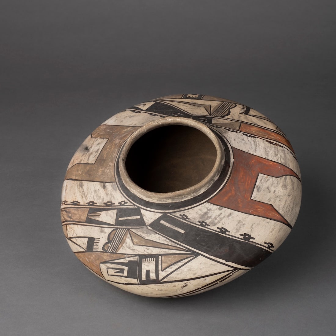 A Hopi Polychrome Seed Jar: Attributed to Nampeyo, decorated on the shoulder with abstract avian designs, with a wide black band just below the shoulder, with trace of an old paper label, and painted inventory number on the bott