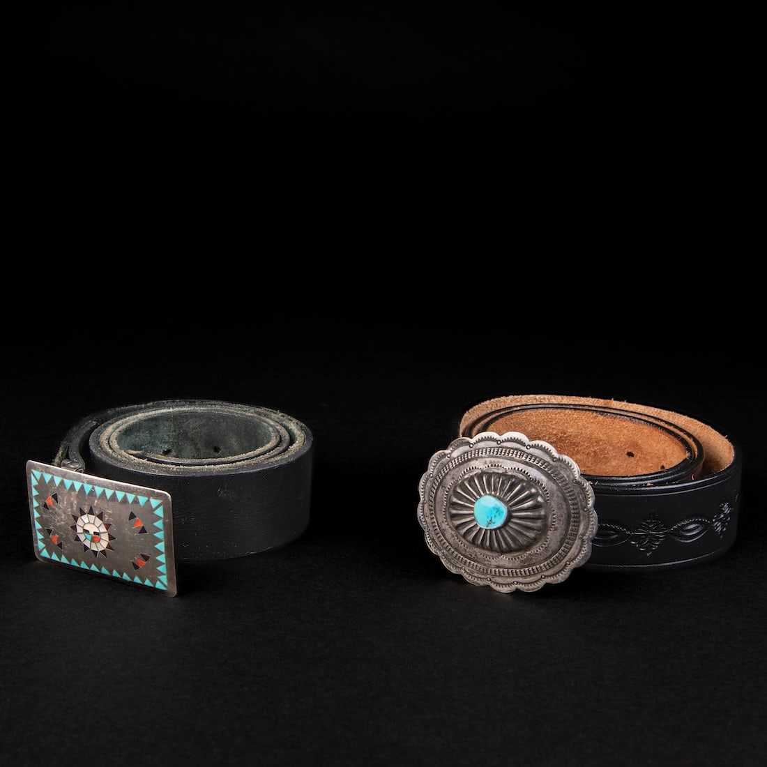 Two Southwest belts with buckles: A Navajo (Diné) silver concha-style belt buckle with turquoise setting, marked "BKS," and a Zuni inlay silver buckle with turquoise, jet, sell and coral decoration. Lg. of belts 44 1/2 and 45 in.