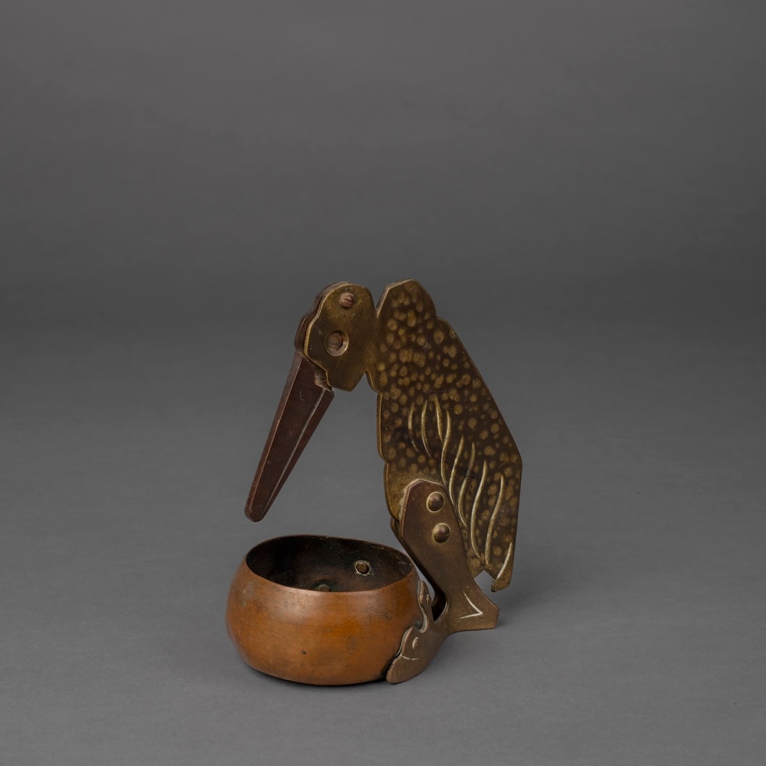 A Brass Cigar Cutter: Early 20th century, the bird with a brass bowl between it’s large feet, the stylized body with a long beak, which raises to expose the cutting hole at the eye. Ht. 6 1/4 in.