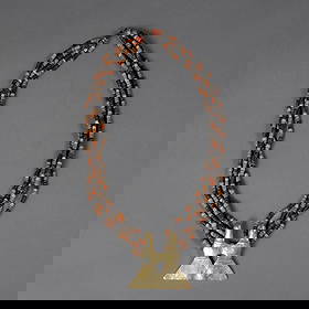 A Pre-Columbian stone bead and gold alloy necklace: Necklace composed of five strands of beads in alternating tan and brown tones, centering a cast gold-alloy pendant of abstract double-form design with triangular base and central perforation. Lg. 12 i