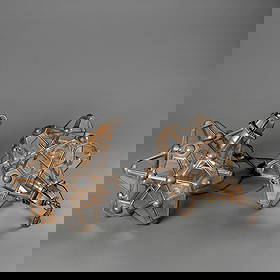 Two Hector Aguilar star chandeliers: Pair of star-form chandeliers, each composed of geometric panes of glass set in copper framework. Includes electrical plug and suspension chains. The metal shows natural patination consistent with age