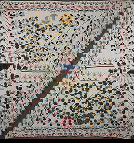 A Colcha textile: Late 18th century, a large pictorial embroidery featuring multicolored floral motifs around a central figure standing in a vase, a man and woman on either side. Celestial symbols depicted at the top a