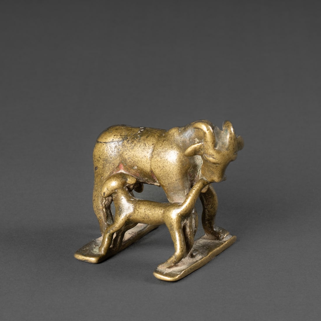 An African bronze animal: Burkina Faso, early 20th century, the cast bronze sculpture depicting a mother goat with a young nursing at her side. The mother holds the young’s tail in her mouth. Both figures rendered with