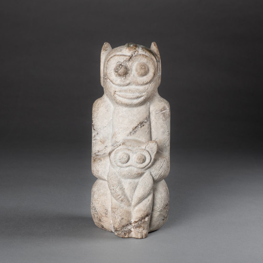 An Erlitou Neolithic Chinese figure: Circa 1900-1500 B.C.E., a stone carved animal figure, crouching and holding a smaller creature in front and the legs, (restoration to cracks in the stone). Ht. 10, wd. 4 x 3 7/8 in. Provenance: Privat