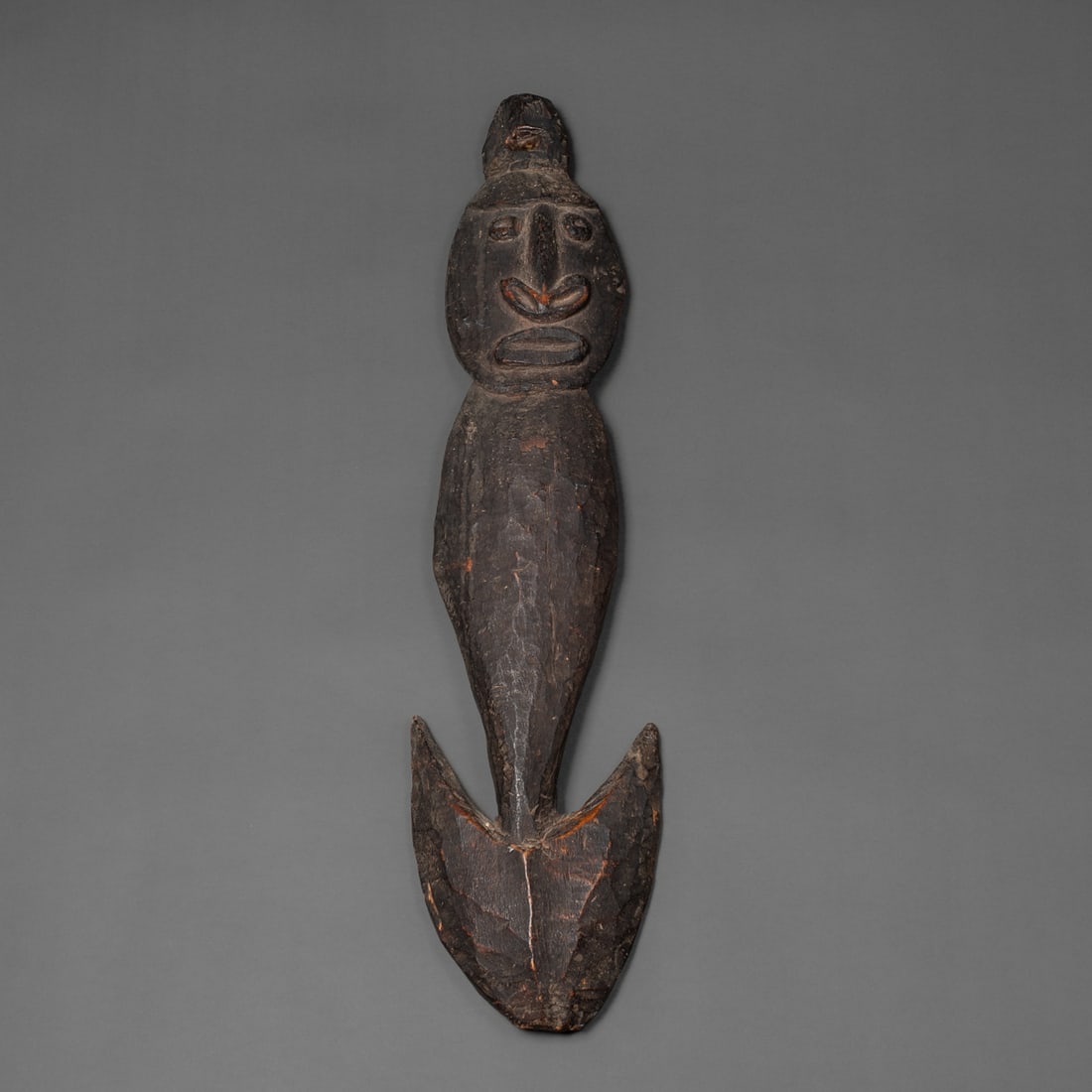 A New Guinea food hook: Sawos, Middle Sepik River, Papua New Guinea, early 20th century, the carved wood hook with plain torso and carved head with exaggerated features, the crown with large pierced lug for suspension. Lg. 2