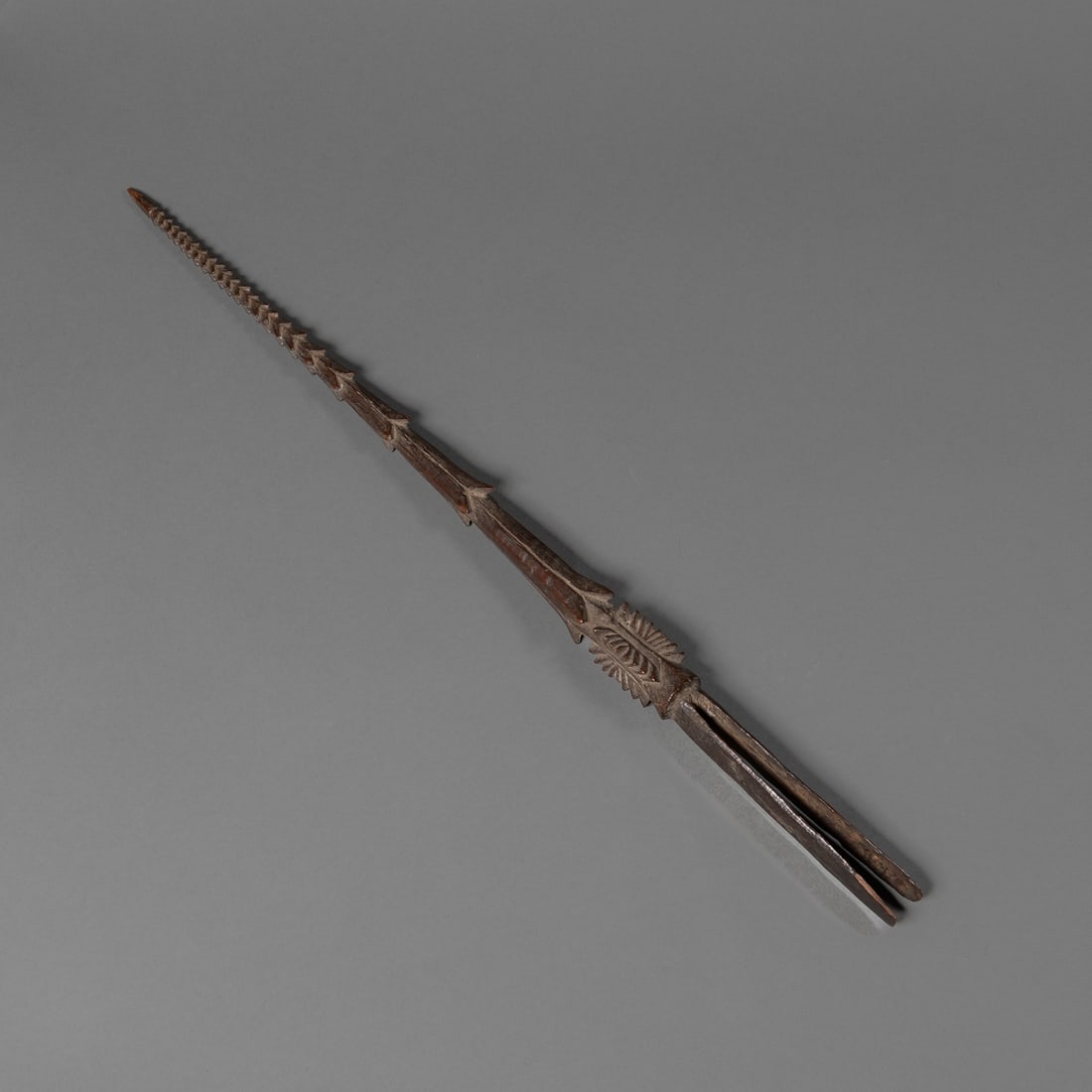 A Fijian spear point: Early/mid-19th century, the finely hand-carved from dense hardwood with deeply incised geometric ornamentation. The surface shows a dark, smooth patina from age and handling. Lg. 23 in. ex. Old Englis