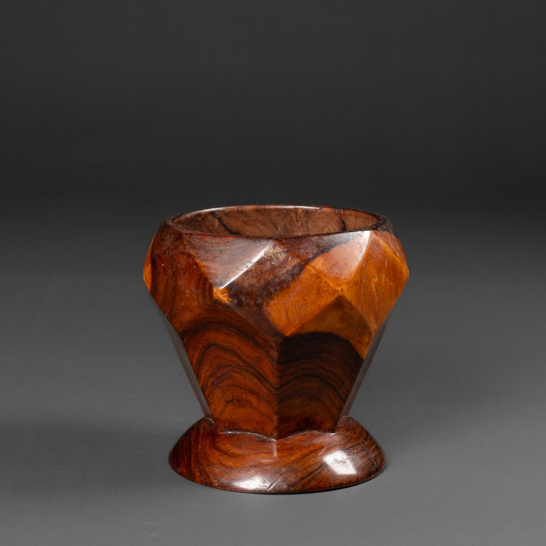 A Hawaiian pedestal bowl: Circa 1870s, made from Kou wood, probably lathe-turned with seven vertical and diamond facets around the circumference. Ht. 5 1/8, wd. 5 3/8 in. Provenance: Private collection, Los Angeles, CA;