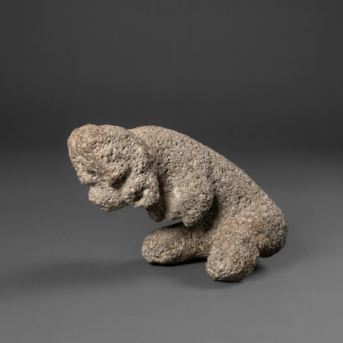 A Hawaiian stone figure: Carved from vesicular basalt, the head with two faces with round, open mouths, short arms below and short legs. Lg. 11 in. Provenance: Private collection, Santa Fe, NM; The Al Luckett Jr. collection,