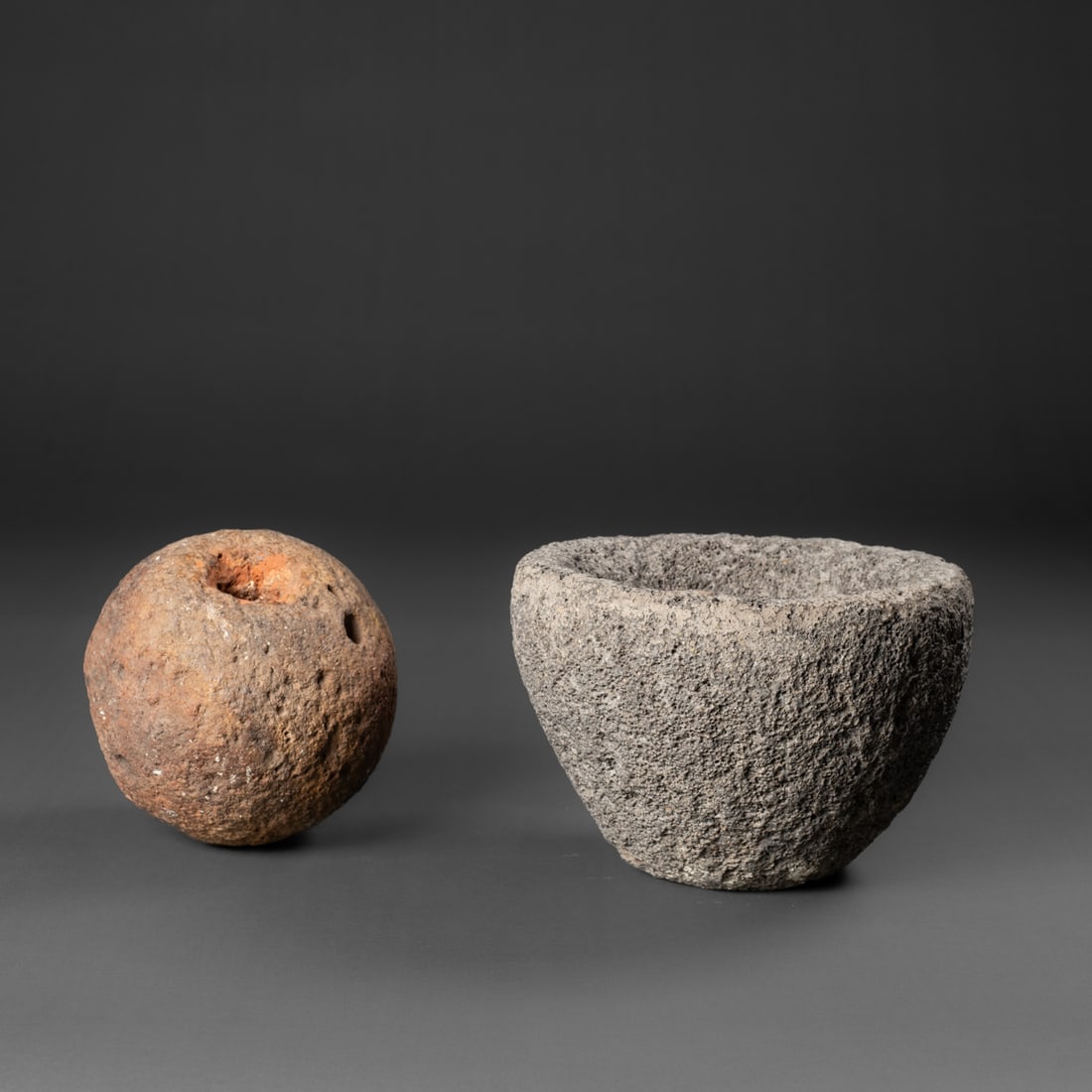 A Hawaiian stone mortar and ball: Carved from basalt, the bowl with tapering sides, with a round stone with a shallow hole. Ht. 5, wd. 7, and wd. 4 1/2 in. Provenance: Private collection, Santa Fe, NM; The Al Luckett Jr. collection,