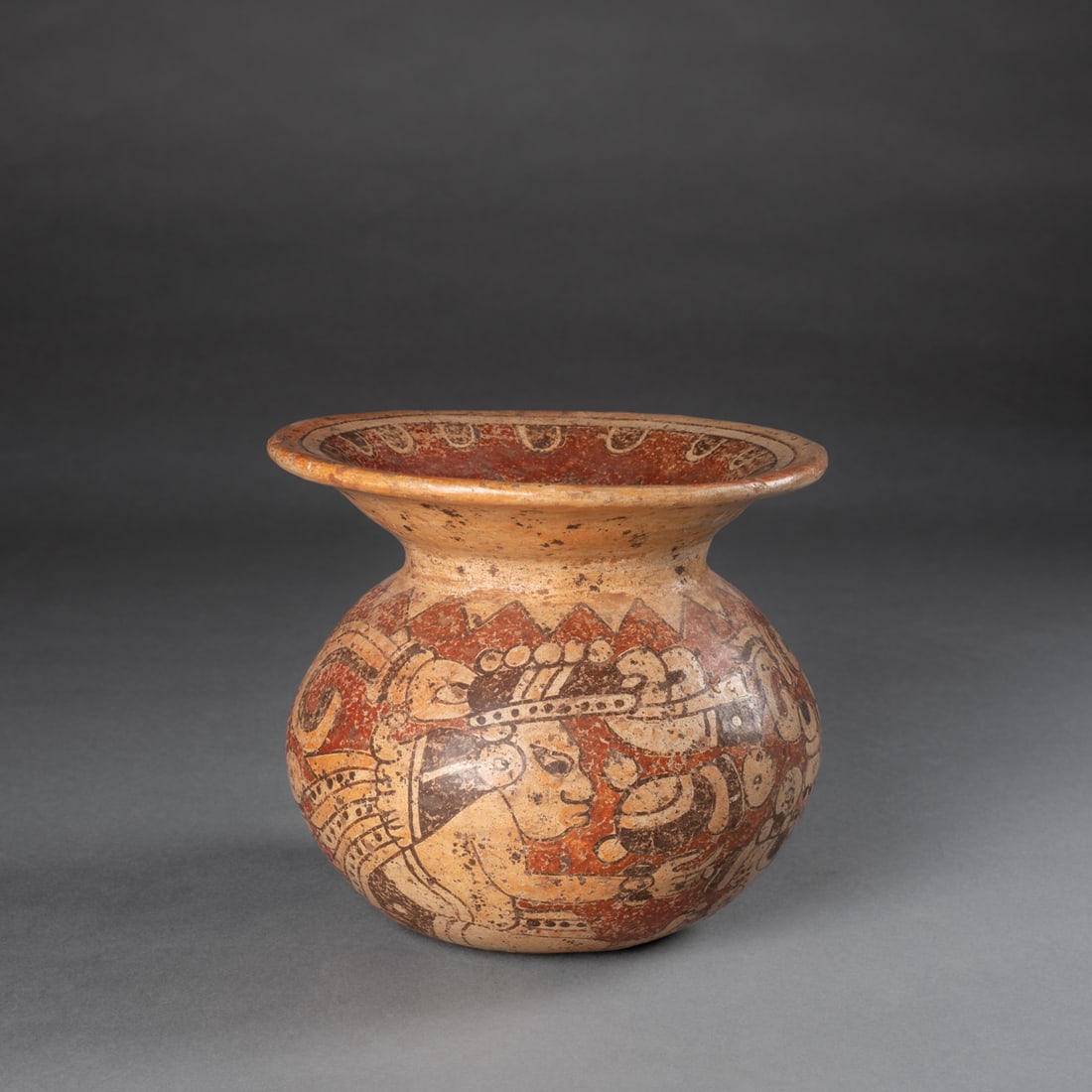 A Pre-Columbian polychrome vessel: Mayan, Honduras, Late Classic, circa 550-950 A.D., the rounded vessel with very wide and flaring rim, fully painted with figurative decorations around the body and star motif at the opening. Ht. 6 1/4