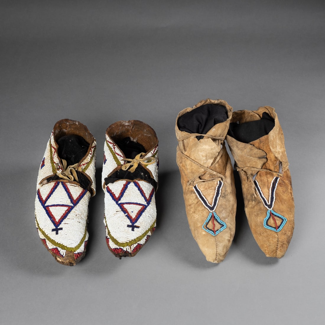 Two pair of Plains beaded hide moccasins: Fourth quarter 19th century, one pair with hard raw hide soles and stiff hide uppers which are fully beaded with multicolored geometric designs on a white ground, the second pair soft hide with bead
