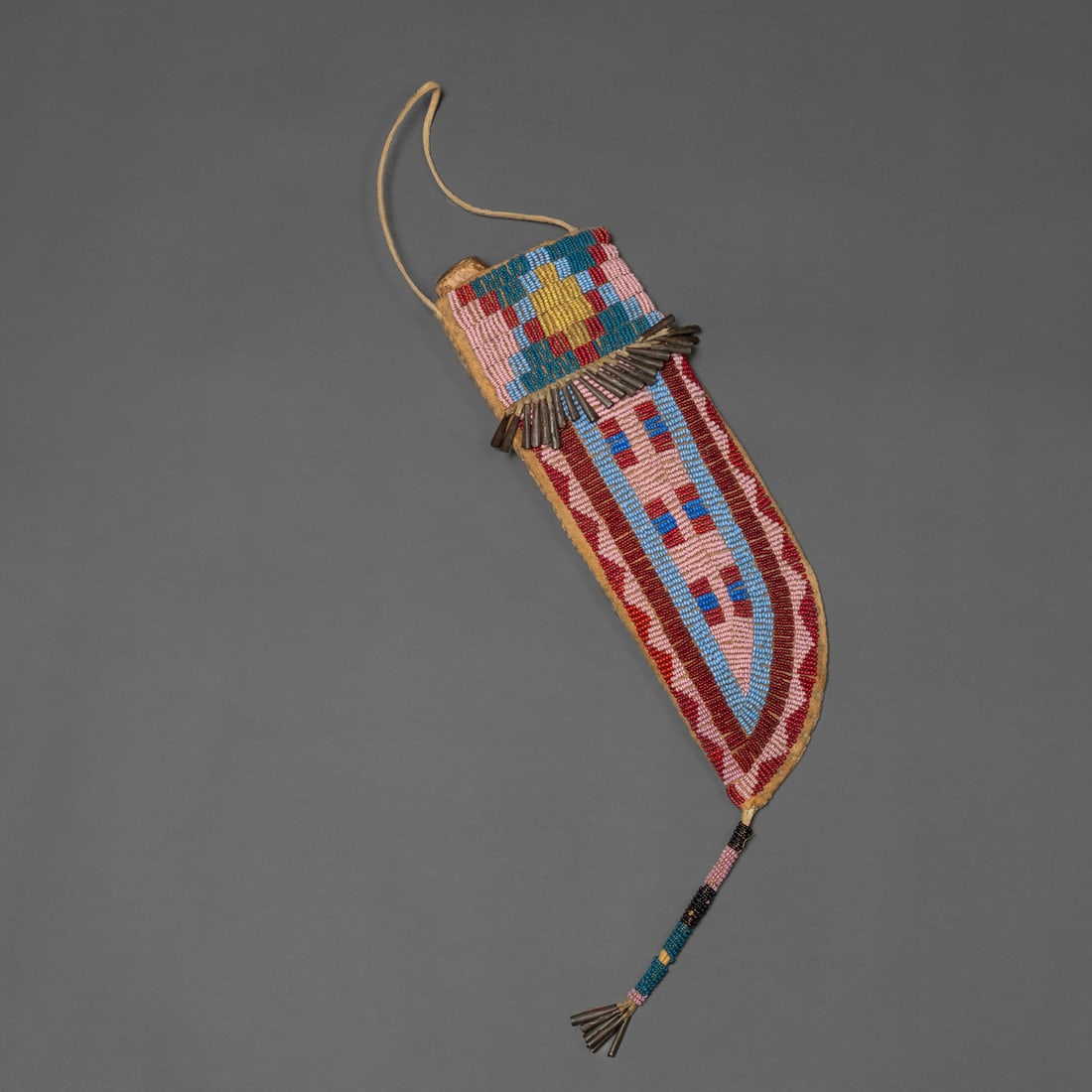 A Plains beaded knife sheath on buffalo hide: Lakota, fourth quarter 19th century, sinew-sewn knife sheath, beaded on soft-tanned buffalo hide with classic Plains geometric designs in shades of red, pink, light blue, greasy yellow, white, and