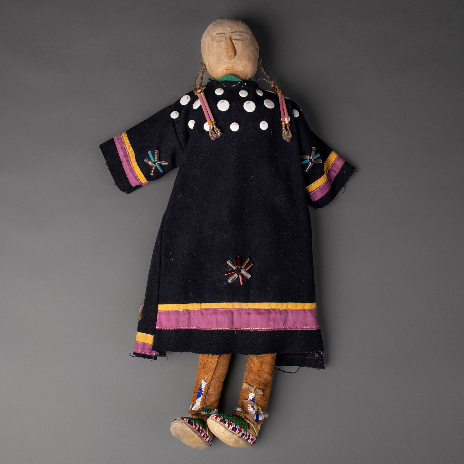 A monumental Northern Plains doll: Lakota (Sioux), early 20th century, cloth, hide, and beaded doll with a trade wood dress emulating elk tooth dresses of the period; fully beaded moccasins, and other adornments. Good condition but