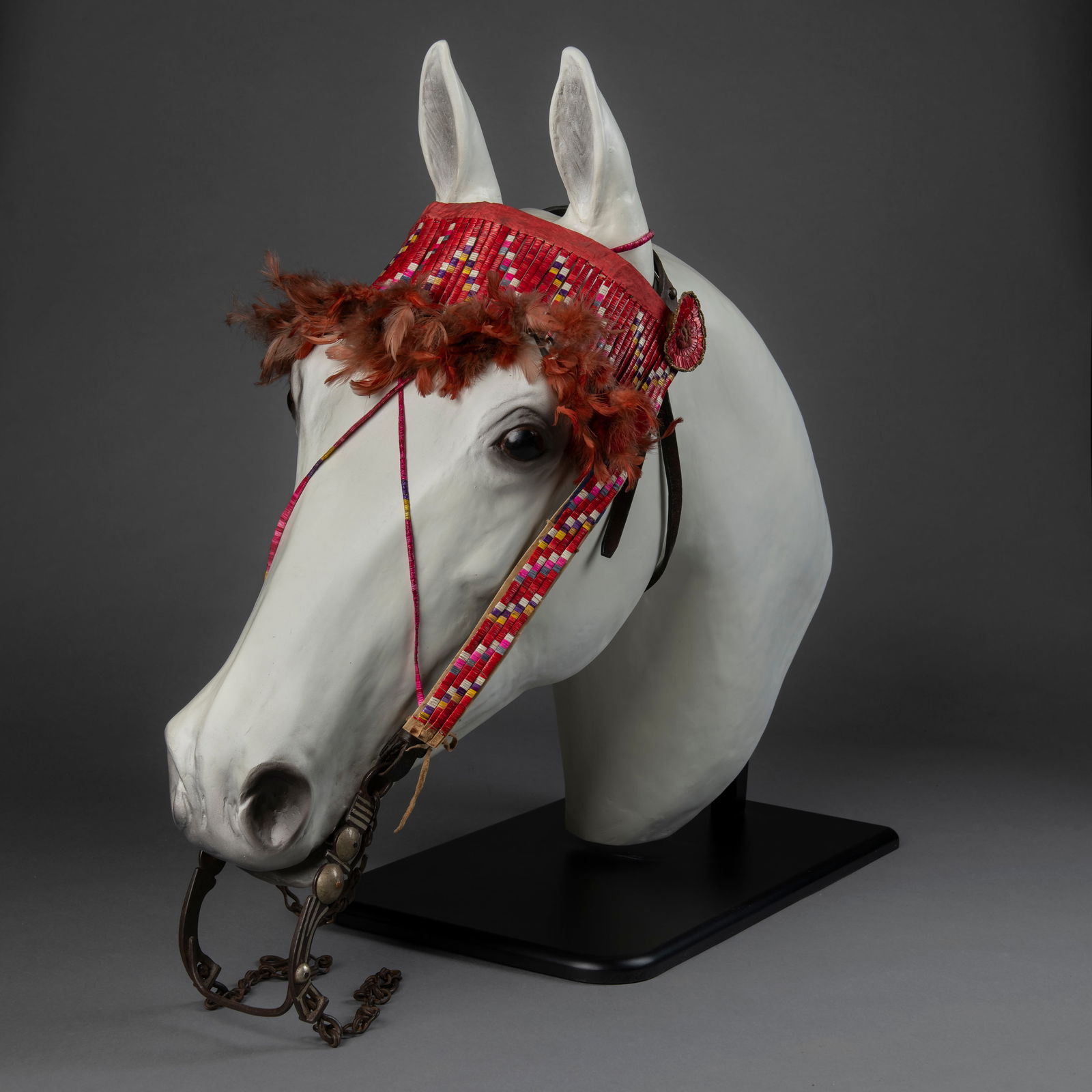 A Plains quilled headstall: Sicangu Lakota (Brule Sioux), fourth quarter 19th century, multicolor quillwork, with feathers and period trade bit with silver inlay, mounted on a resin horses head. Browband lg. 16 in. Overall